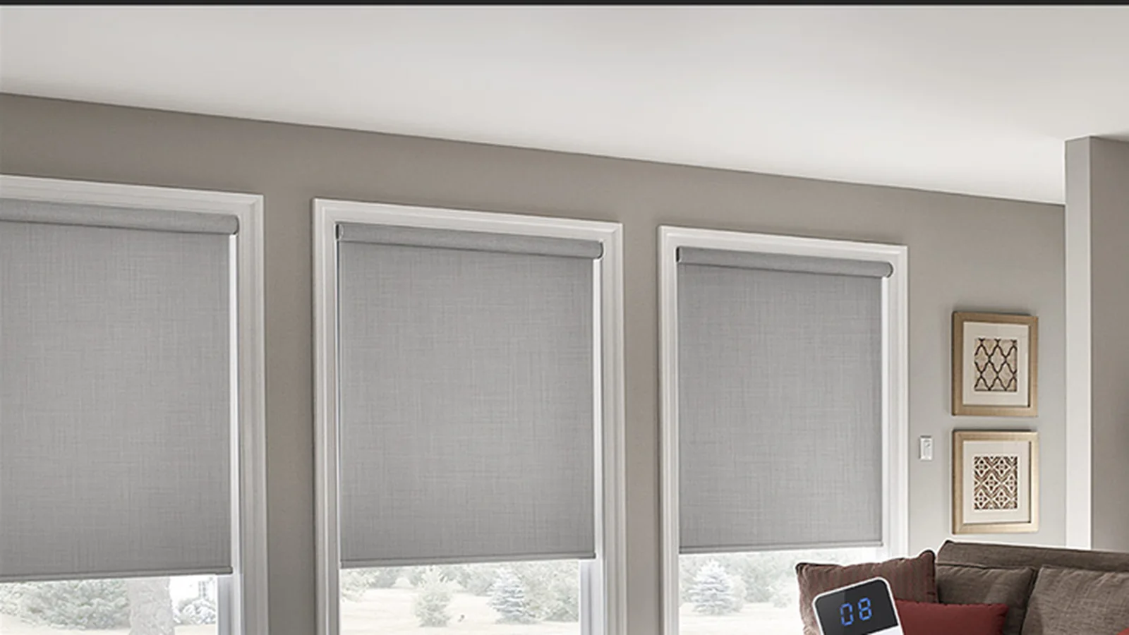 Hand using a remote control to operate motorized roller shades in a living room